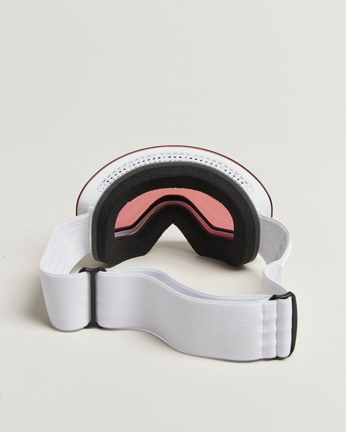 White ski goggles with pink lens from behind