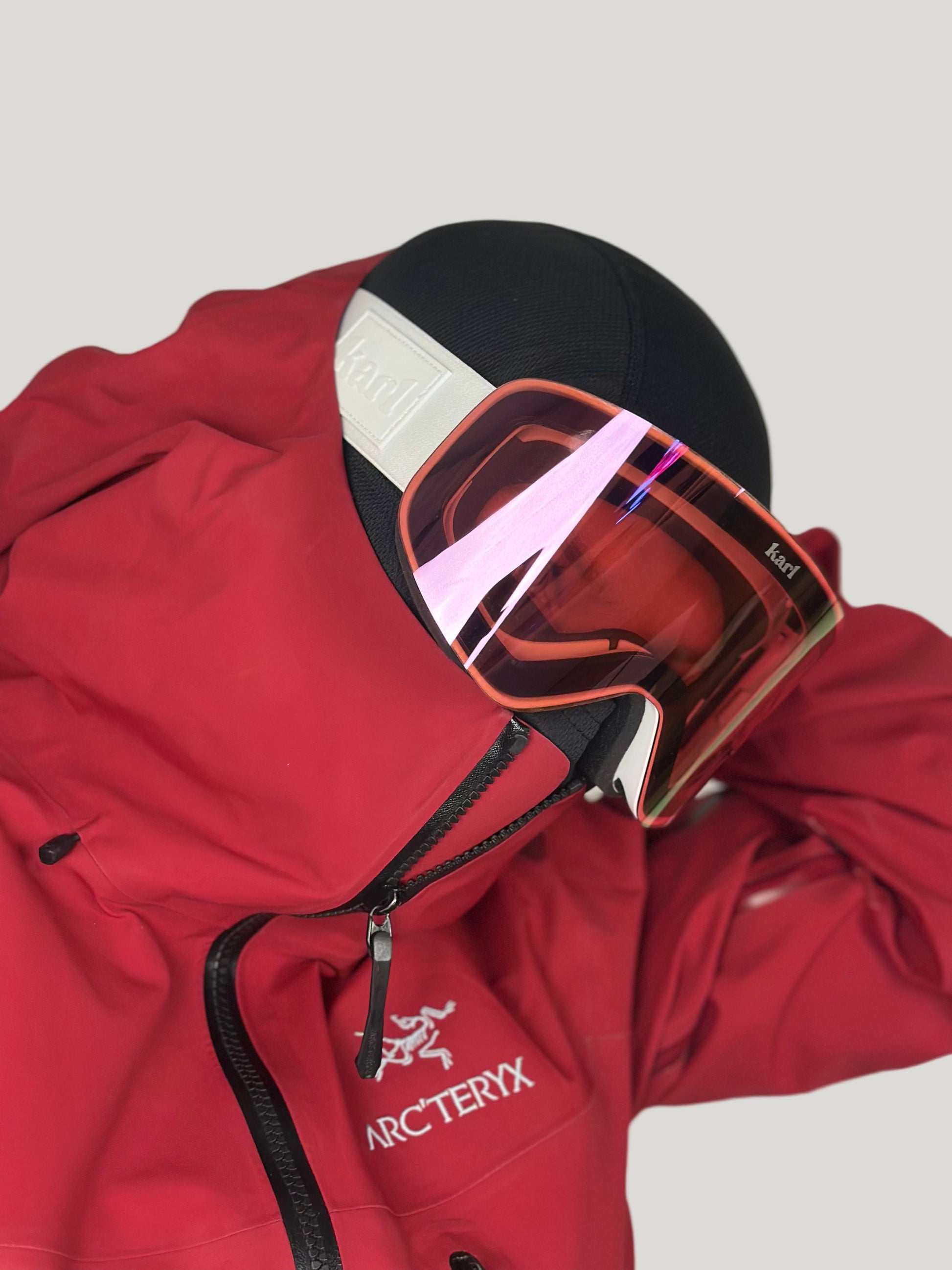 Red jacket with a hood and white goggles with pink lens on a neutral background
