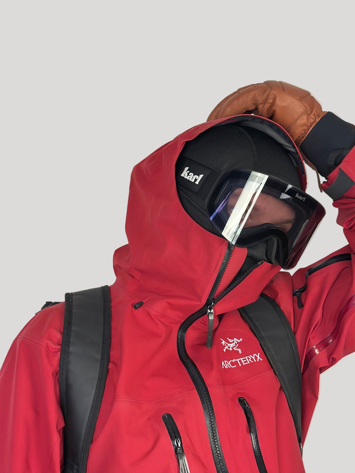 Person wearing a red jacket with a helmet and goggles, featuring Arc'teryx branding.